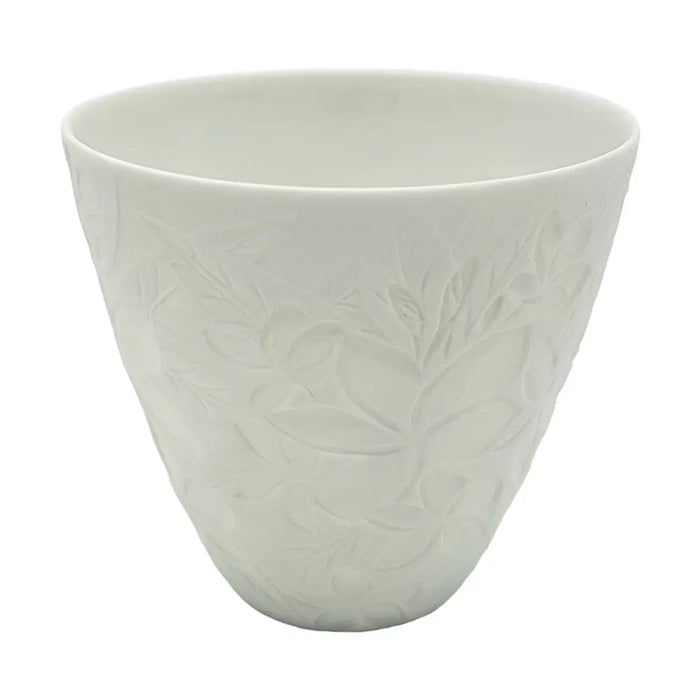 A white porcelain tealight holder with a subtle embossed floral frangipane design in a simple ceramic cup shape