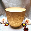 A warm translucent beige ceramic vase with embossed floral pattern in a white porcelain tealight holder design