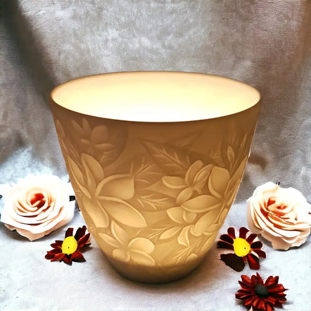 A warm translucent beige ceramic vase with embossed floral pattern in a white porcelain tealight holder design