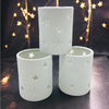 White porcelain tealight holders with star design cutouts shown in two sizes for votive candles