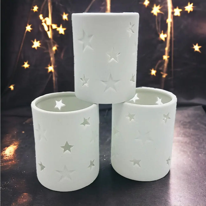 White porcelain tealight holders with star design cutouts shown in two sizes for votive candles