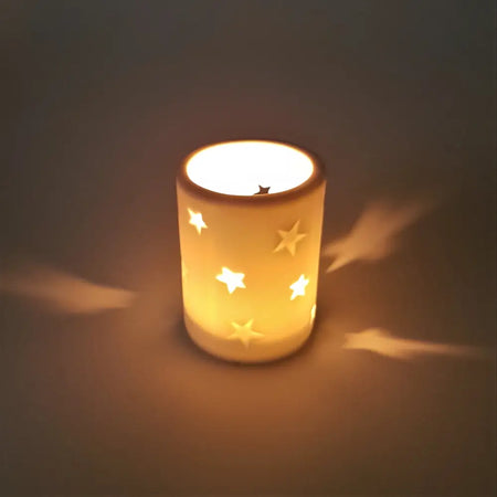 A warm glowing white porcelain tealight holder with star design cutouts available in two sizes
