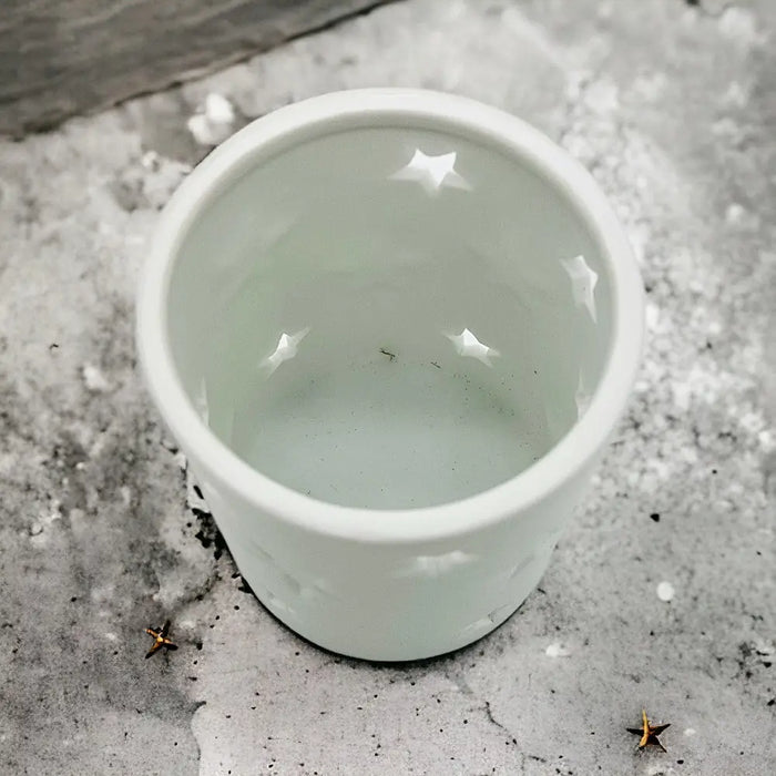 White porcelain tealight holder with star design cutouts shown in one of two sizes for votive candles