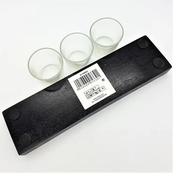 Black wooden block candle holder with three clear glass votive or tealight cups on a white background