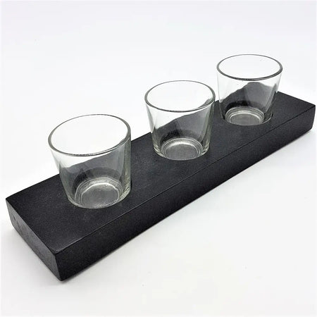 Black wooden block holding three clear glass votive and tealight holders on a rectangular tray