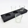 Black wooden block serving tray with three circular indentations holding clear glass votive tealight holders