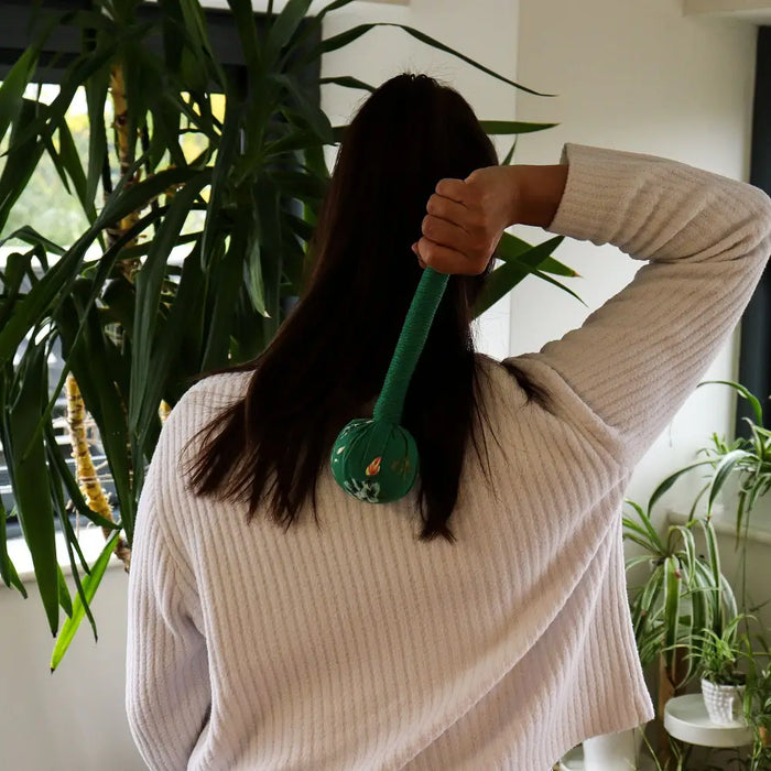 Green wormwood massage hammer with spherical textured handle designed for easy grip and deep massage relief