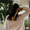 A vibrant yellow wormwood massage hammer with a textured handle being used on a back for wormwood massage relief
