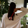 Red and white patterned wormwood massage hammer with a long handle for deep tissue massage and muscle relief