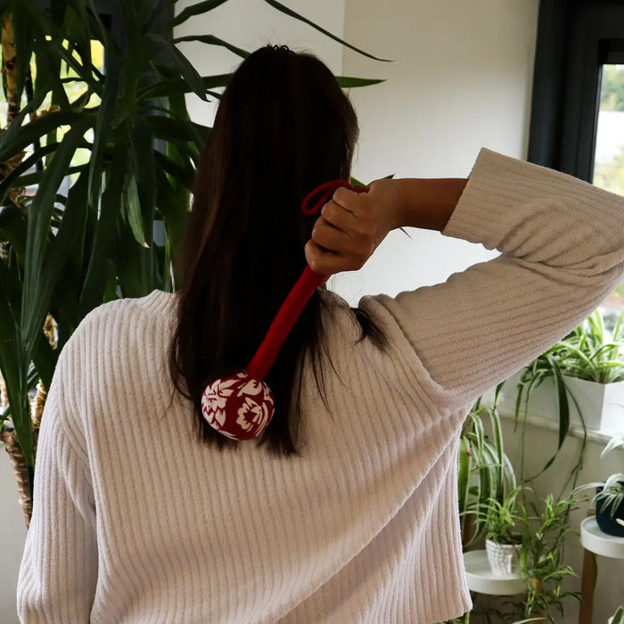 Red and white patterned wormwood massage hammer with a long handle for deep tissue massage and muscle relief