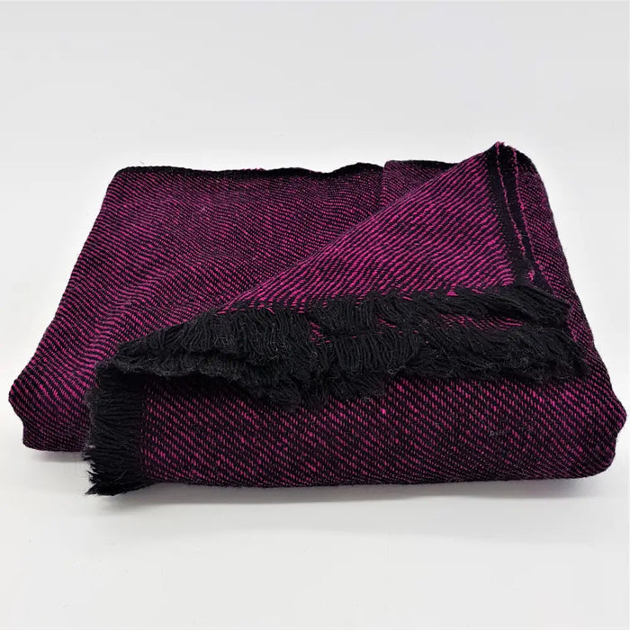 Folded woven woollen shawl and throw in purple and black with a herringbone pattern and fringed edges