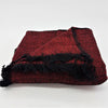 Red and black woven woollen throw blanket with fringed edges laid out flat on a plain background