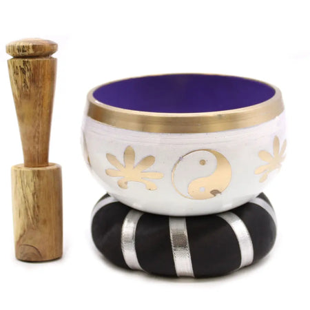 White tibetan singing bowl set with gold yin yang symbol, floral designs, purple interior, and brass rim