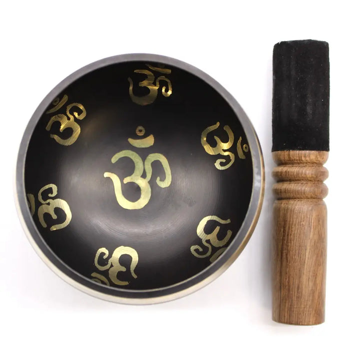 Black singing bowl set with gold om symbols and wooden mallet for yoga and meditation use
