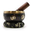 Black tibetan singing bowl set with gold om symbols brass rim and dark wood mallet for yoga and meditation use