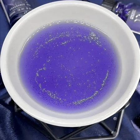 A white ceramic bowl with shimmering purple liquid and gold glitter showing zodiac fragrance oil Pisces 10ml